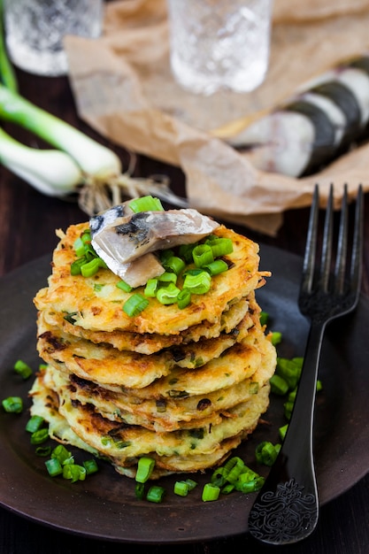 Frittelle di patate con aringa e cipolla su sfondo scuro