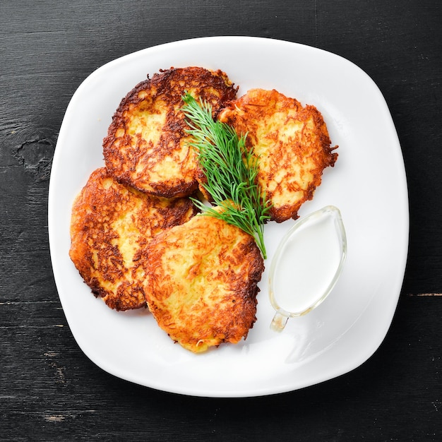 Frittelle di patate con panna acida. Cucina tradizionale ucraina. Vista dall'alto. Spazio libero per il tuo testo. Stile rustico.