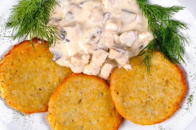 Frittelle di patate con ragù di carne su un piatto bianco e fondo bianco isolato