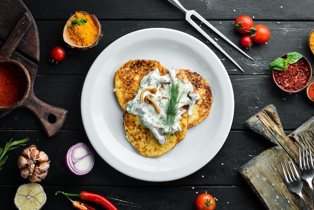 Frittelle di patate con salsa di funghi. Su uno sfondo di legno. Vista dall'alto. Spazio libero per il tuo testo.