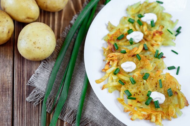 Frittelle di patate fritte o draniki con panna acida e cipolla verde. Il piatto nazionale di Bielorussia, Ucraina e Russia.