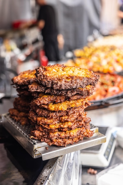 Frittelle di patate fritte tradizionali ammucchiate al venditore durante un mercato di cibo di strada