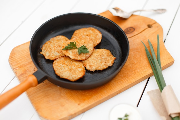 Frittelle di patate su una padella di ghisa con cipolle e prezzemolo