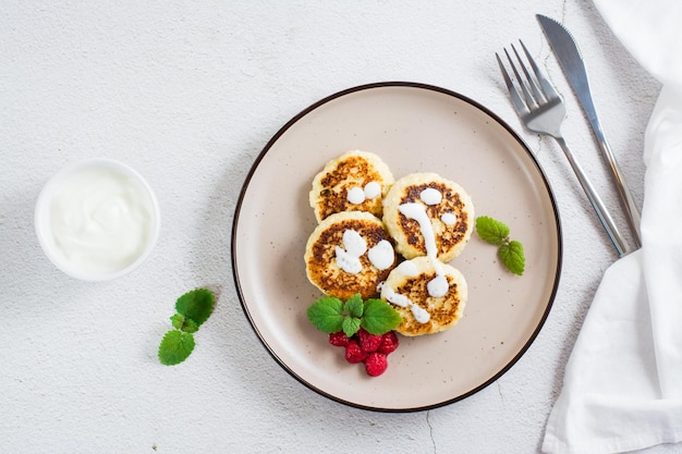 Frittelle di ricotta con lamponi di panna acida e menta su un piatto sul tavolo Vista dall'alto