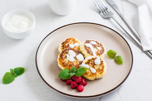 Frittelle di ricotta con lamponi panna acida e menta su un piatto sul tavolo Primo piano