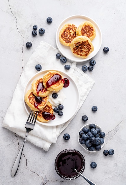 Frittelle di ricotta con marmellata di mirtilli panna acida e mirtilli vista dall'alto flat lay