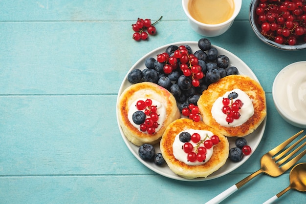 Frittelle di ricotta con ribes e mirtillo. Caffè, frutti di bosco e salsa