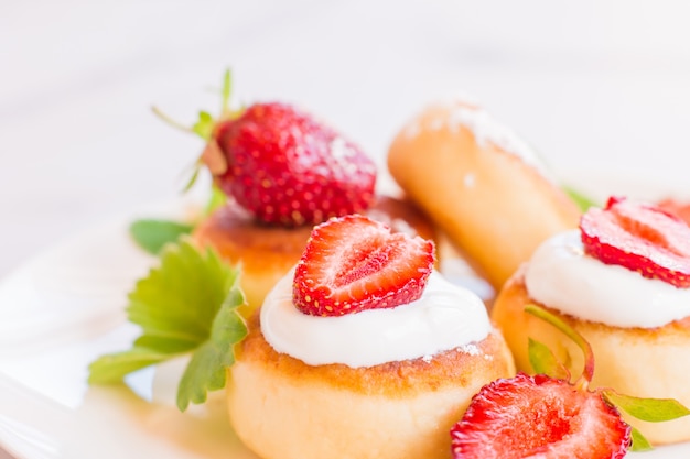 Frittelle di ricotta, syrniki, frittelle di ricotta con fragole. Colazione gourmet. sfondo bianco