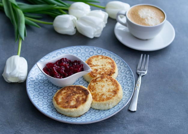 Frittelle di Syrniki, ricotta o ricotta con marmellata di ciliegie e caffè su grigio