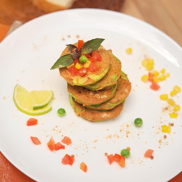 Frittelle di verdure di frittelle di zucchine servite su un piatto al caffè all'aperto