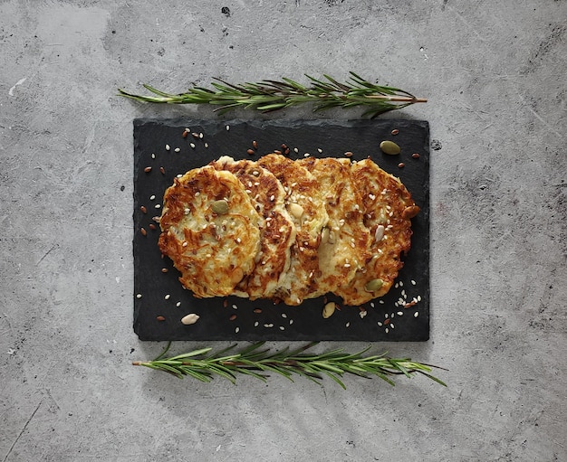 Frittelle di zucchine con rametti di rosmarino su sfondo chiaro, vista dall'alto, distesi.