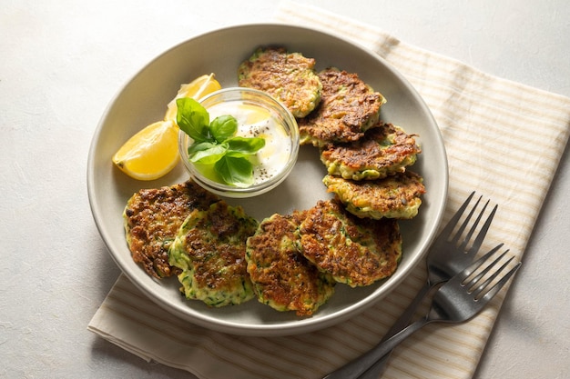 Frittelle di zucchine o frittelle di zucchine vegetariane servite con salsa allo yogurt