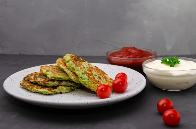 Frittelle di zucchine vegetali servite con yogurt e salsa di pomodoro