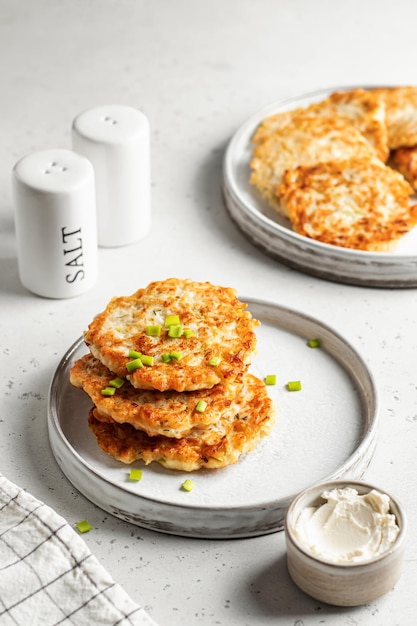 Frittelle di zucchine vegetariane cosparse di cipolle verdi con sale e pepe e tovagliolo a scacchi