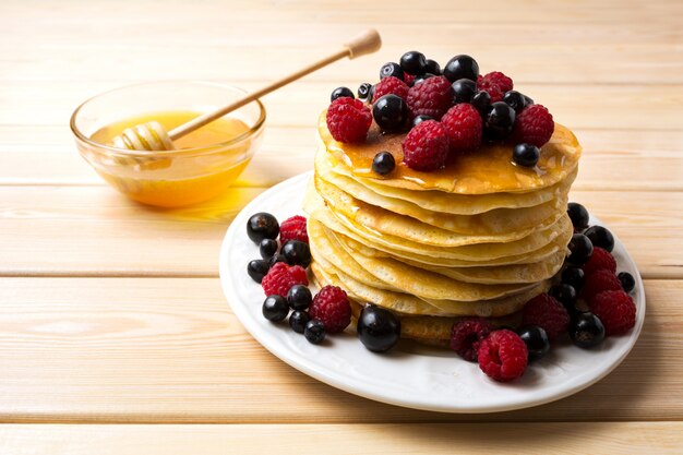 Frittelle fatte in casa con miele e frutti di bosco freschi