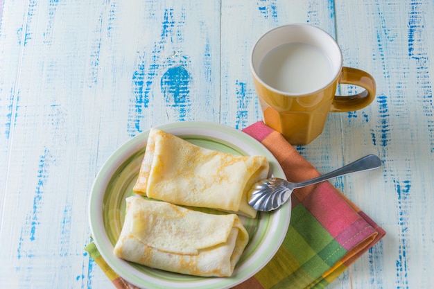 Frittelle fatte in casa con un ripieno e una tazza di latte su uno sfondo di legno