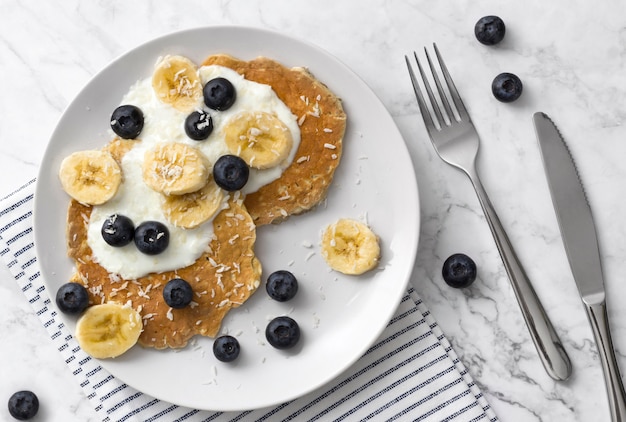 Frittelle sane con bacche fresche, frutta e yogurt. Concetto di colazione estiva.