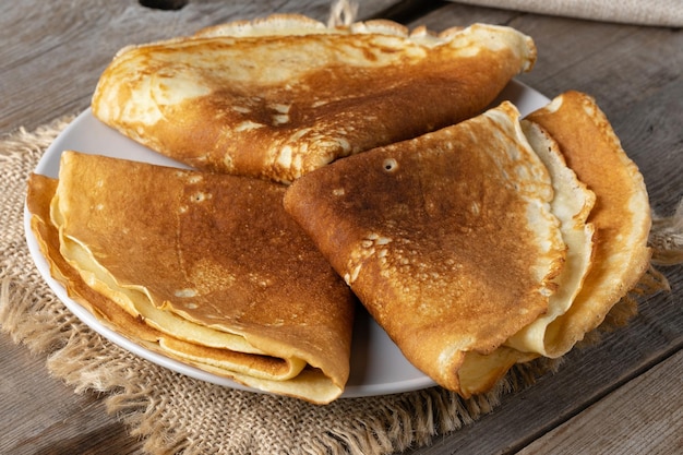 Frittelle sottili su un piatto su un vecchio tavolo di legno