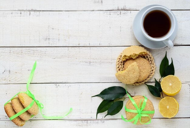 Frollini al gusto di limone biscotti un nastro verde rotto e collegato per un regalo Limone fresco su uno sfondo bianco di legno La vista dall'alto