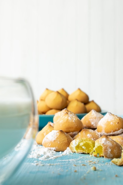 Frollini con ripieno di marmellata vista di biscotti dolci al forno e un bicchiere di latte fuoco selettivo