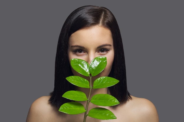 Fronte del primo piano di giovane bella donna con foglia verde.