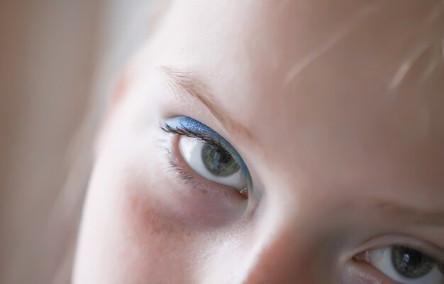 Fronte della ragazza dell'adolescente con il trucco. Ombretti blu. Avvicinamento.