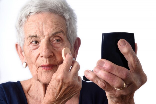 Fronte di trucco della donna maggiore su priorità bassa bianca