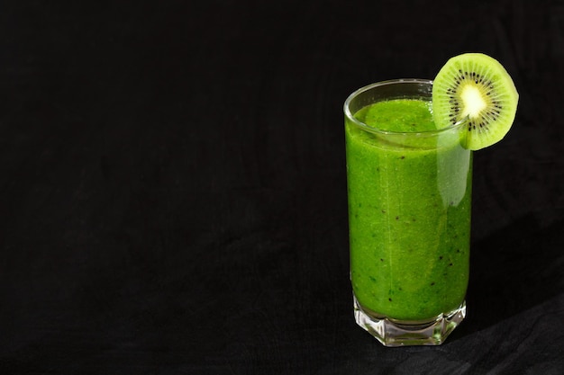 Frullare una densa bevanda verde con kiwi su sfondo nero