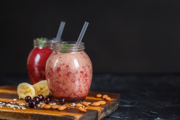 Frullati appena preparati di banana con melograno e banana con mora in bottiglia. Dieta, stile di vita sano