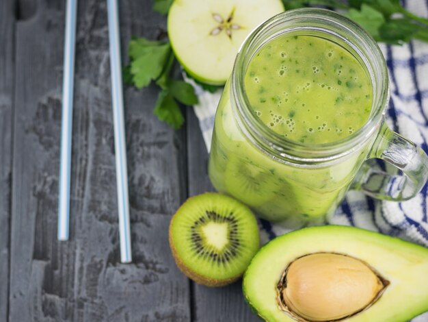 Frullati di avocado appena fatti con erbe e due cannucce da cocktail su un tavolo di legno. Dieta cibo vegetariano.