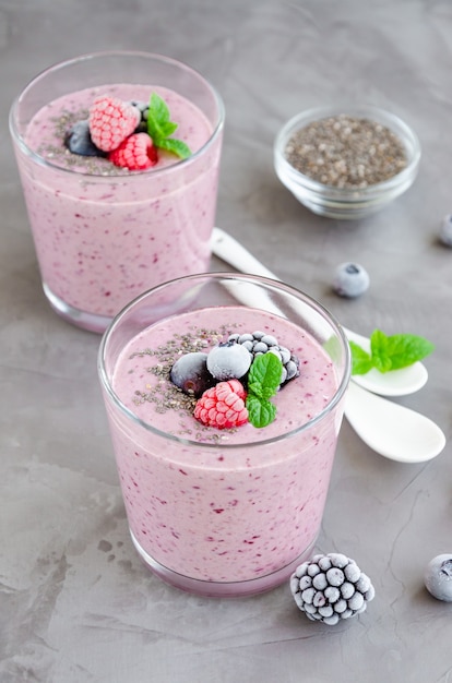 Frullati di bacche di yogurt, semi di chia e frutti di bosco congelati in un bicchiere al buio