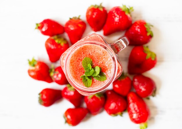 Frullati di fragole o fragole con ghiaccio in un barattolo. Una bevanda estiva rinfrescante. Sfondo bianco. Vista dall'alto. Copia spazio