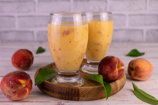 Frullati di pesche fresche biologiche in bicchieri per su un vassoio di legno.