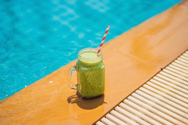 Frullati verdi di spinaci e banana sullo sfondo della piscina frullati sani cibo sano