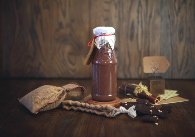 Frullato al cioccolato in bottiglia. Bevanda colorata in bottiglia con cioccolato biologico e supercibi su uno sfondo di legno. Mangiare sano e pulito, vegano, vegetariano, disintossicante, spuntino dietetico per la colazione