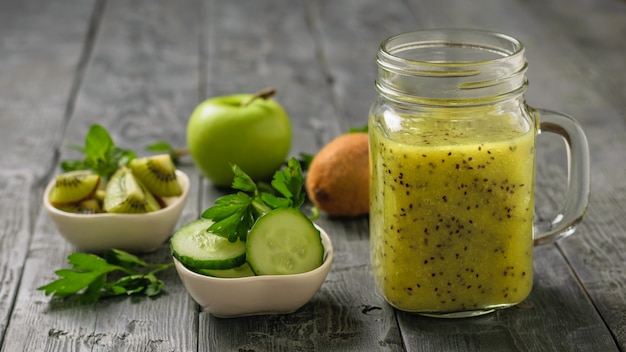 Frullato appena preparato delle fette del kiwi, della mela e del cetriolo e del cetriolo sulla tavola rustica