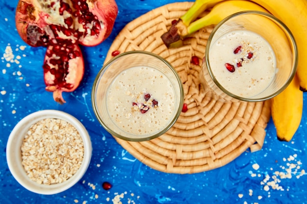 Frullato con avena o farina d'avena, banana e melograno su blu.