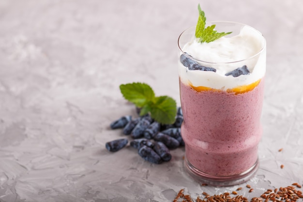 Frullato con caprifoglio, lino e chia in un bicchiere su cemento grigio