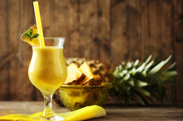 Frullato di ananas in bicchiere da cocktail su fondo di legno