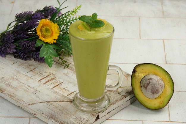 frullato di avocado con frutta di avocado intera e a fette su sfondo bianco