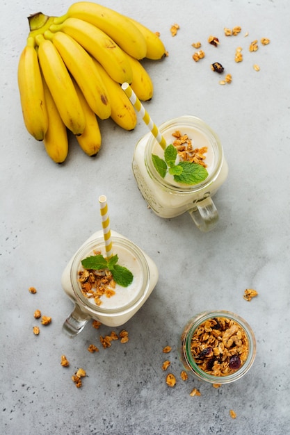 Frullato di banana con muesli, frutta secca e menta su una superficie di cemento grigio. Vista dall'alto.