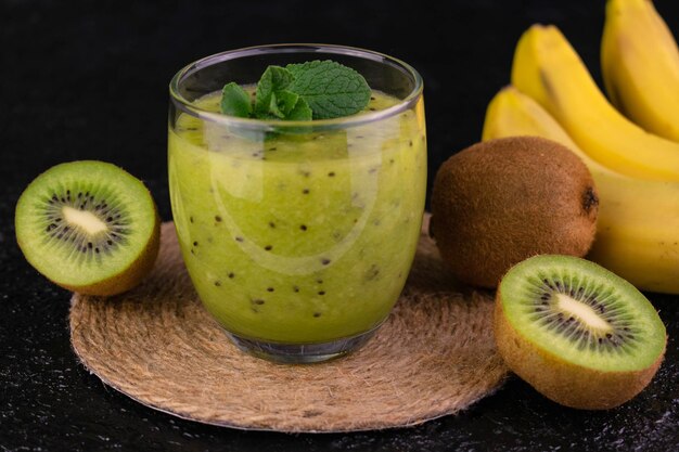 Frullato di banana kiwi in un bicchiere su sfondo nero Primo piano