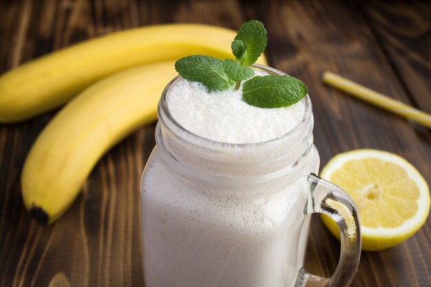 Frullato di banana nel bicchiere sullo sfondo di legno marrone. Primo piano.