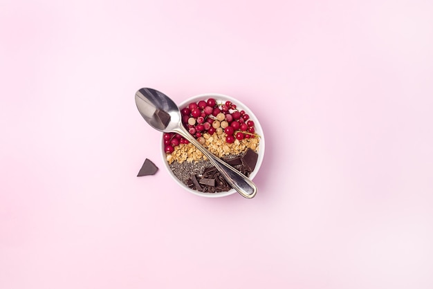 Frullato di ciotola per colazione sana con granola, ribes rosso, semi di chia, cioccolato fondente vegano