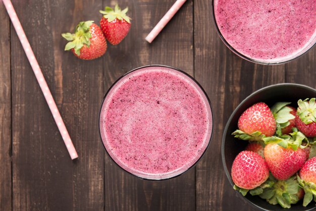 Frullato di fragole e fragole fresche in vetro su fondo di legno.