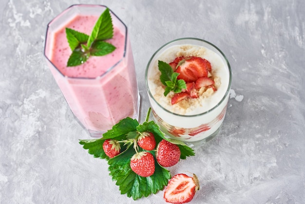 Frullato di fragole in barattolo di vetro e fragole fresche su una superficie grigia