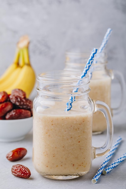 Frullato di frutta alla banana e dattero o frullato in barattolo di vetro su uno sfondo di pietra grigia