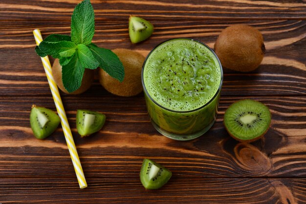 Frullato di kiwi fresco sano in vetro su uno sfondo di legno