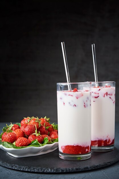 Frullato di latte alla fragola in vetro con paglia e frutti di bosco freschi