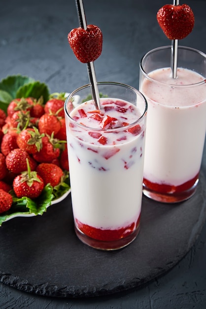 Frullato di latte alla fragola in vetro con paglia e frutti di bosco freschi